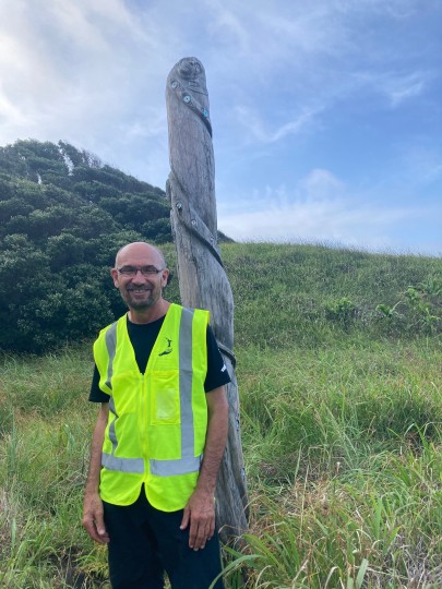 Peter Bellingham beside a pou whenua (boundary marker) that Ngāti Kuri kaumātua installed on Rangitāhua in 2001.